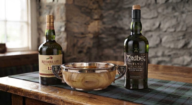 A quaich drinking cup on a table with a bottle of Redbreast 12 and a bottle of Ardbeg Ten whiskies.